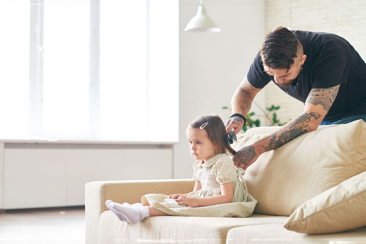 Caring father combing little daughter's hair (Getty Images/mediaphotos)