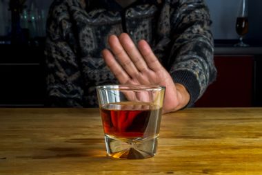 Male hand rejecting glass with alcoholic beverage