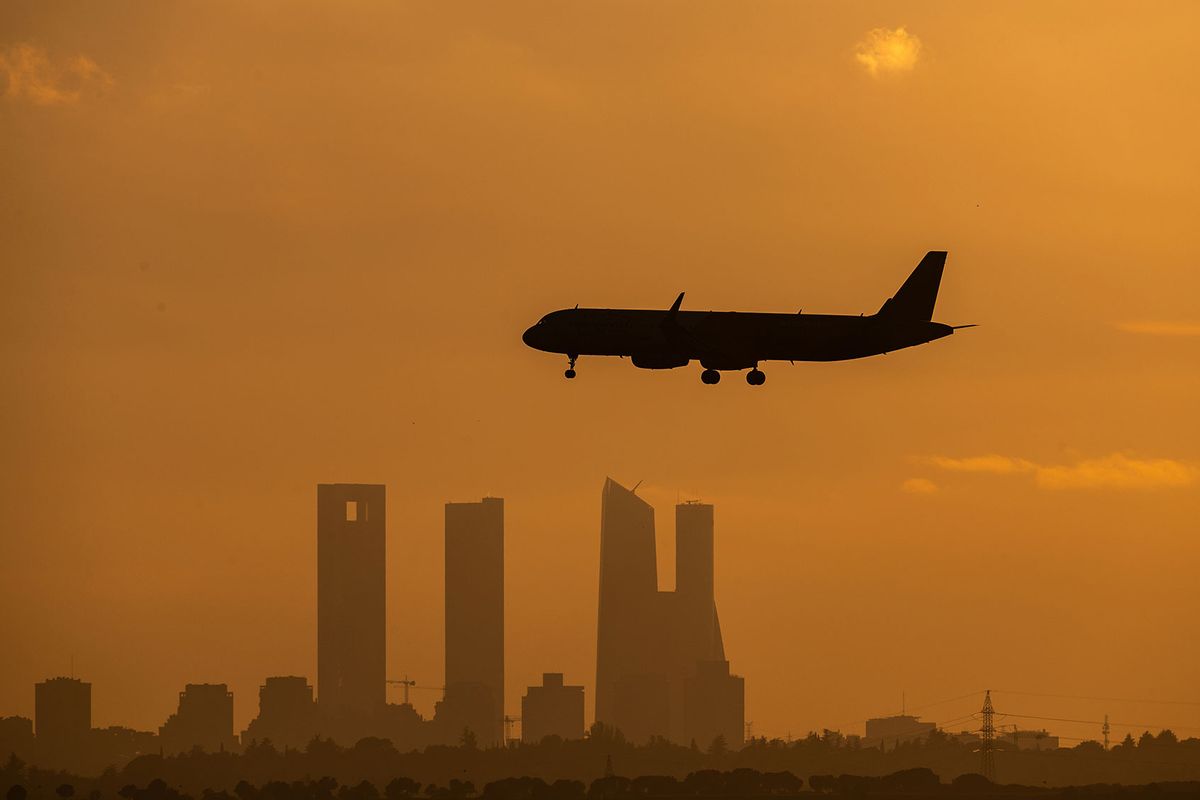 The silhouette of a commercial airplane flies over skyscrapers (Marcos del Mazo/LightRocket via Getty Images)