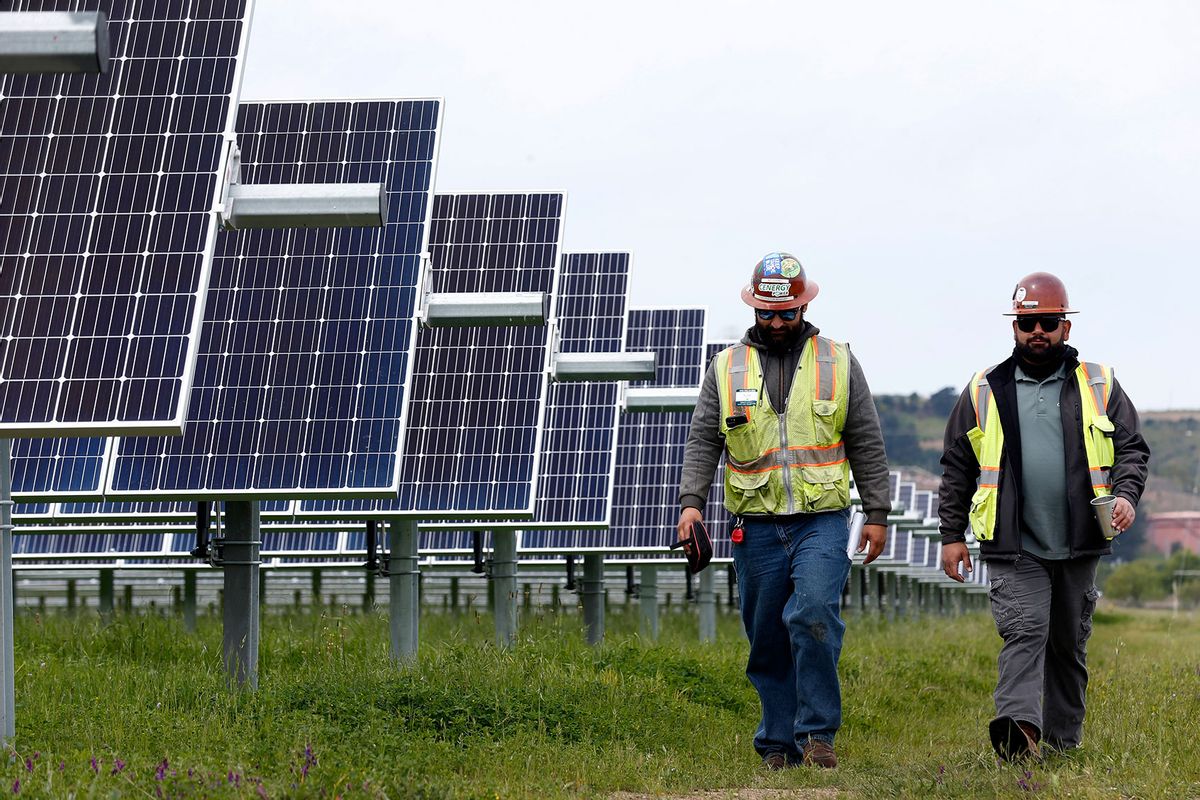 Rey Espino (left) and Croll Envieh, who both worked on the construction of the solar farm, walk past rows of panels on land leased at the Chevron refinery in Richmond, Calif. on Wednesday, April 18, 2018. (Paul Chinn/The San Francisco Chronicle via Getty Images)