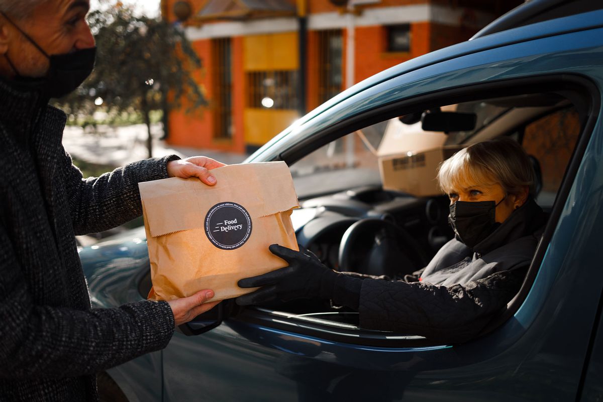 A courier delivers a food order to a customer (Getty Images/Georgijevic)